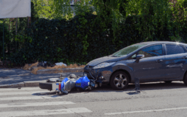 Car and fallen motorcycle after collision at intersection, illustrating road accident, vehicle damage, and traffic safety risks