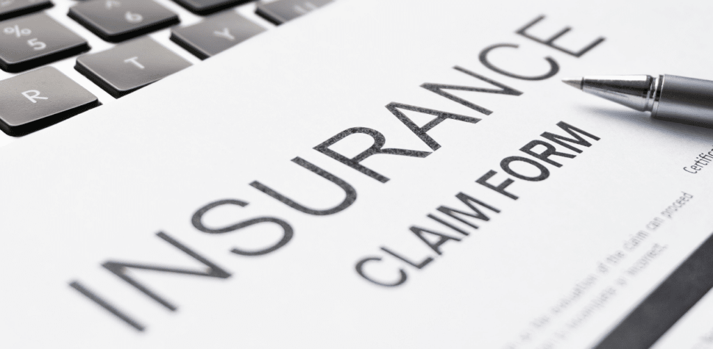 Close-up of an insurance claim form placed on a keyboard, with a pen resting beside it