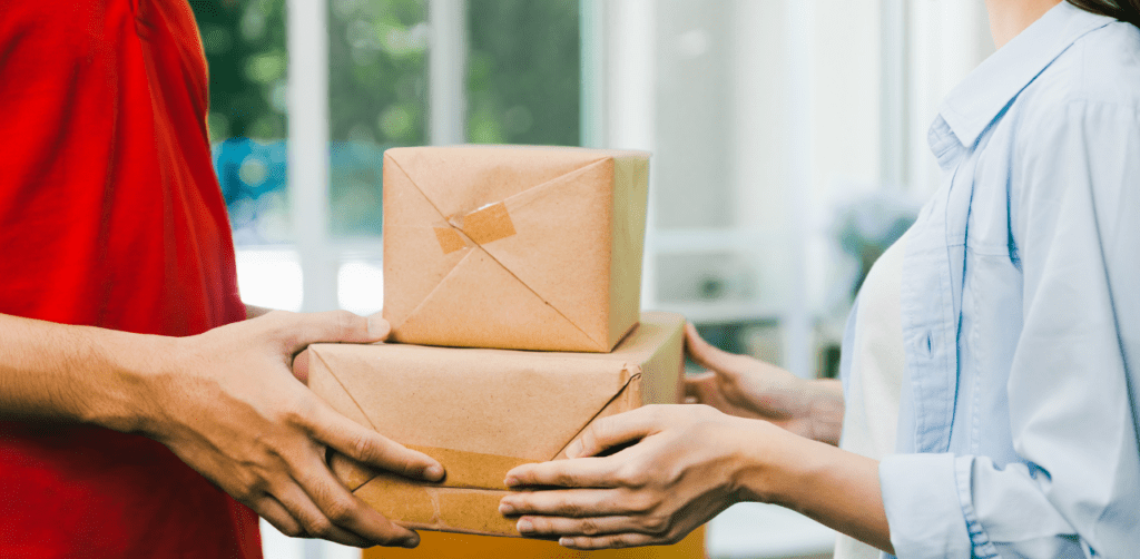 Two people exchanging packages wrapped in brown paper; one person is handing the packages to another
