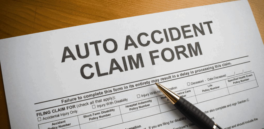 Auto accident claim form with a pen on table, ready for filing an insurance or injury claim