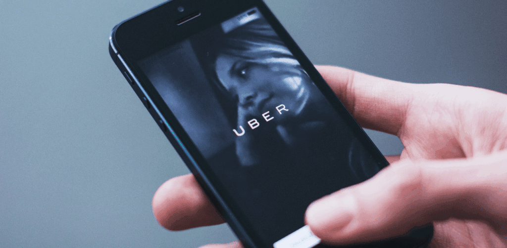 Hand holding smartphone with Uber app open, preparing to request a rideshare trip