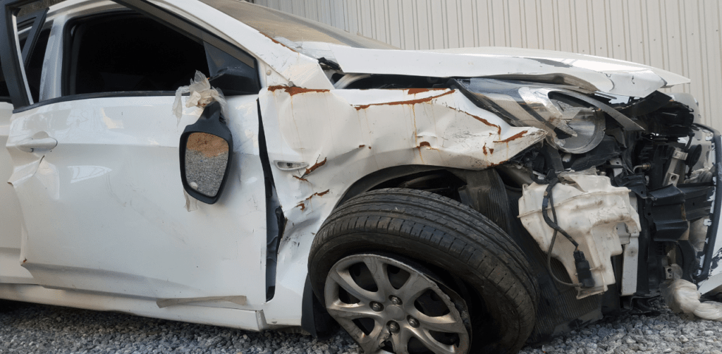 Damaged white car with crushed front end, illustrating injury risk tied to Casino Escalator Accident Claims