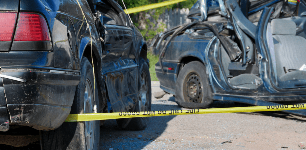 Severely wrecked cars behind caution tape, representing accident scenes linked to Casino Escalator Accident Claims