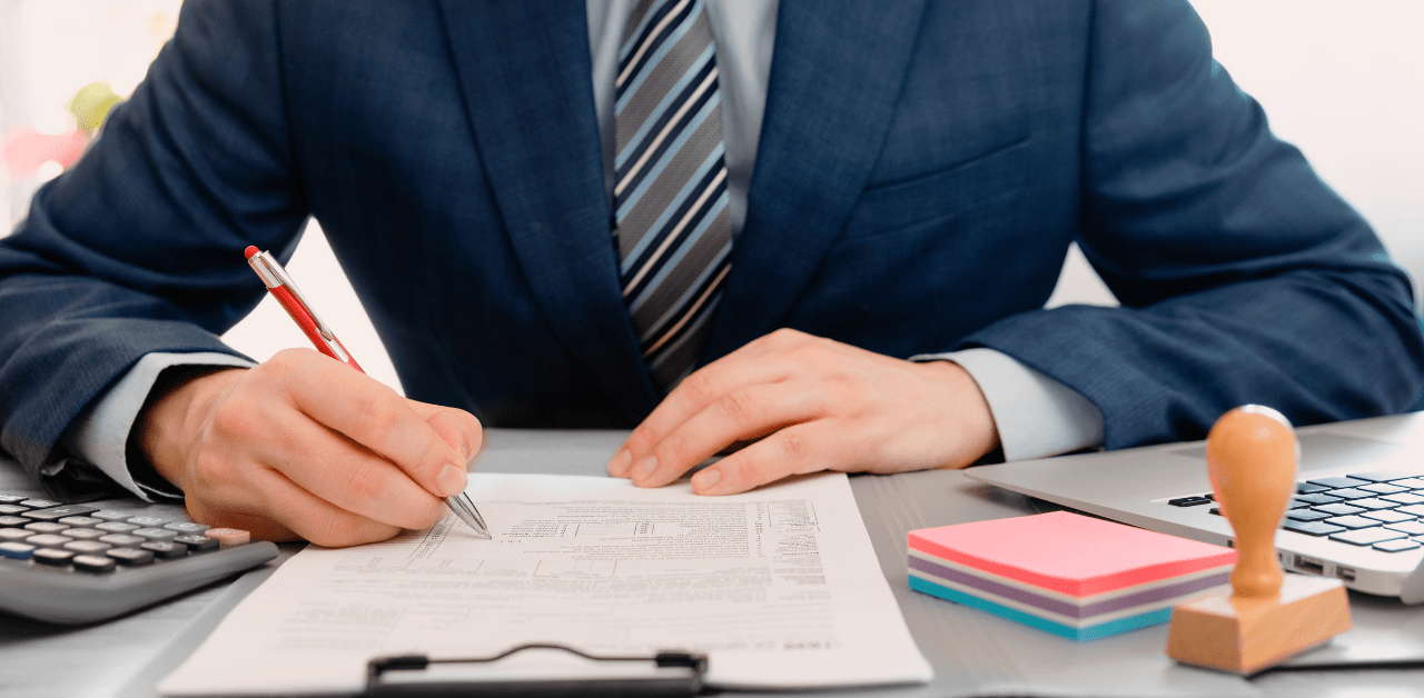 Lawyer in suit signs legal paperwork at desk, representing personal injury claim or accident compensation case