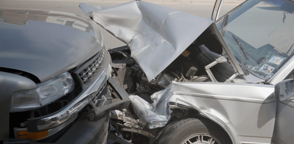 Close-up of two heavily damaged vehicles after a severe front-end collision on a roadway